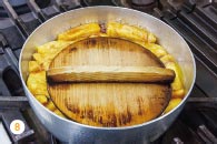 8 Fried tofu in a vat filled with broth and covered with a drop lid.